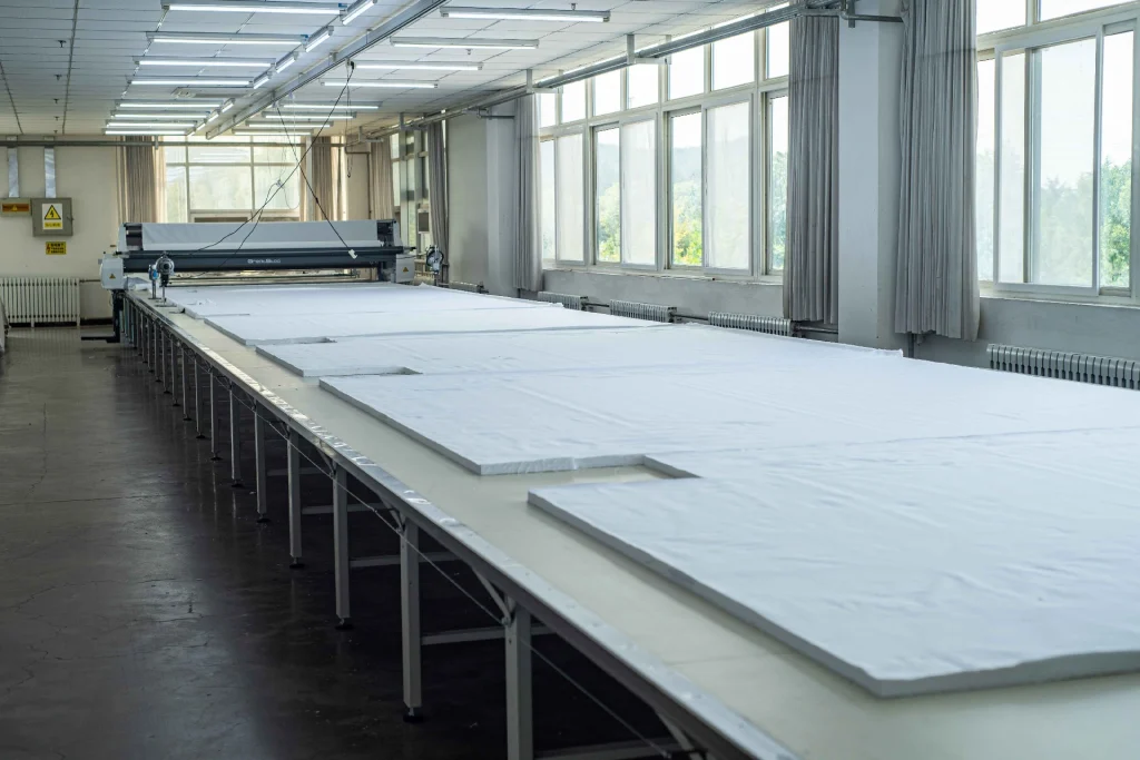 A long cutting table in a bright, empty factory hall.