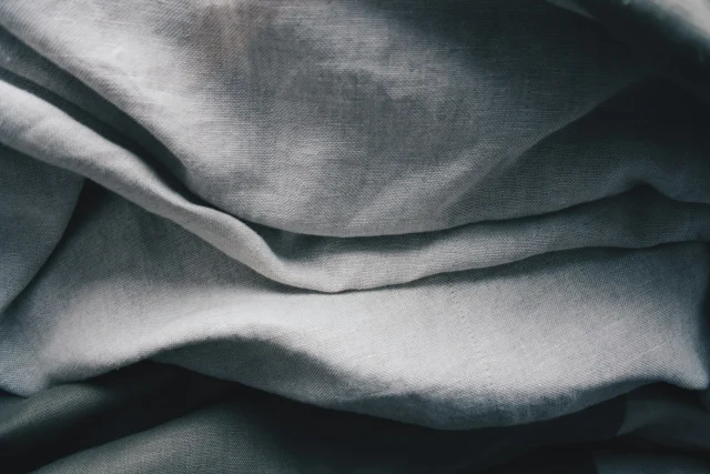 Gray-blue linen in loose folds, with its slubby weave visible.