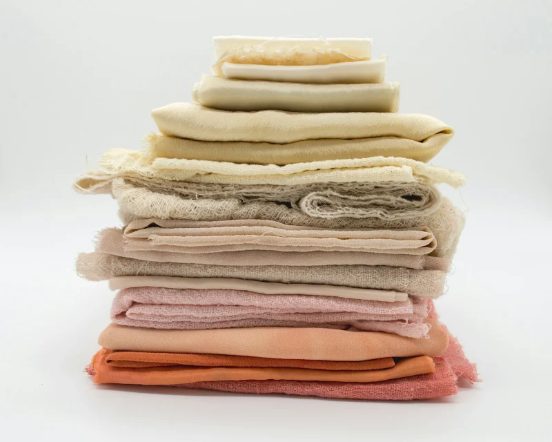 A stack of folded fabrics in pastel shades.