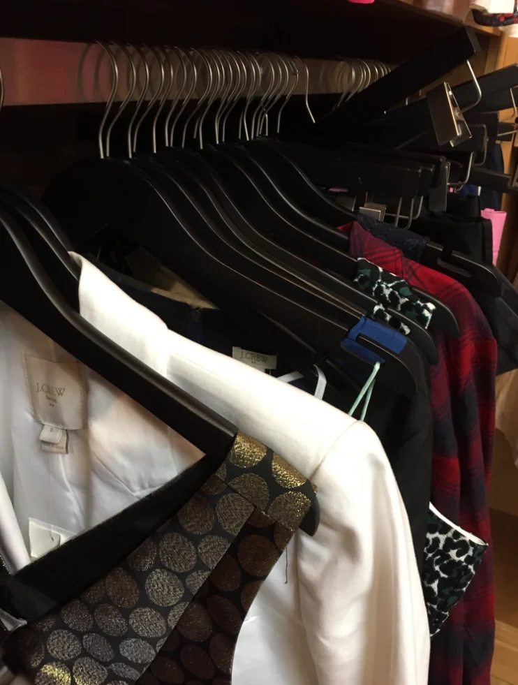 Jackets and shirts on black hangers packed along a wholesale rack.