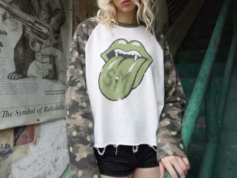 Model wearing a white graphic raglan top with camouflage sleeves.