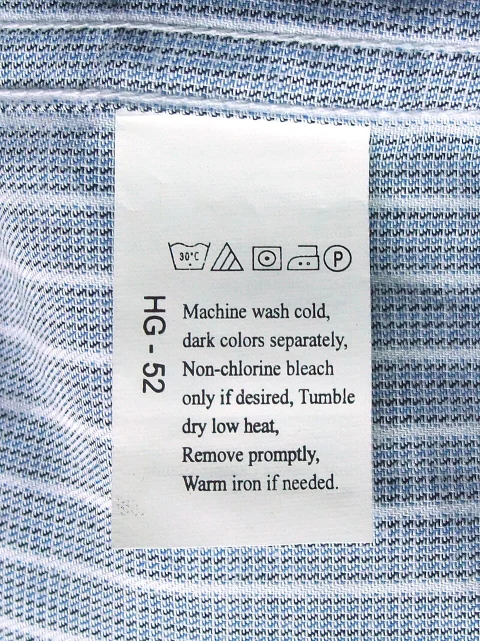 A sewn care label showing laundering symbols and written washing, drying, ironing and dry-cleaning instructions.