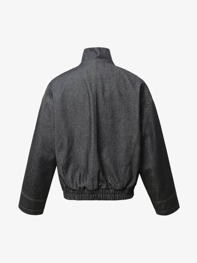 The back of a washed black work jacket with an elastic hem and dropped shoulders.