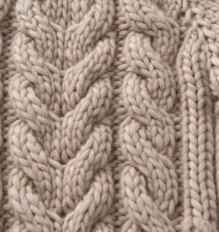 Close view of a chunky knit with raised cables crossing in a repeat.
