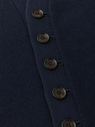 Navy knit cardigan front band with a column of brown buttons.