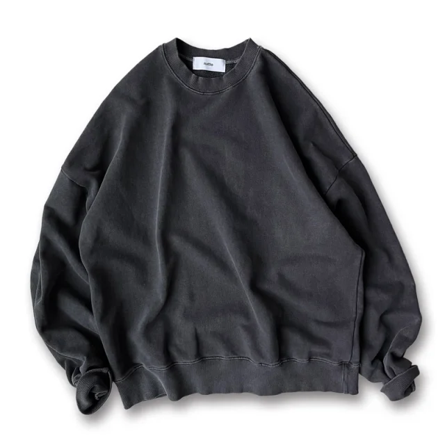 A charcoal washed crewneck sweatshirt, faded unevenly at the seams, collar, cuffs and hem.