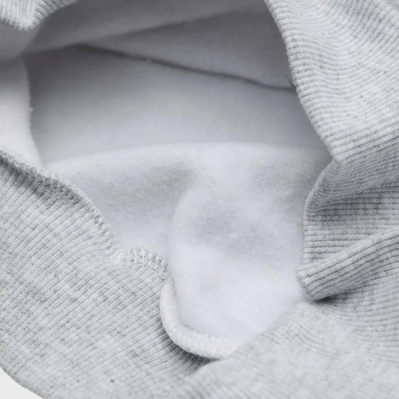The soft brushed inside of a gray sweatshirt beside its ribbed trim.