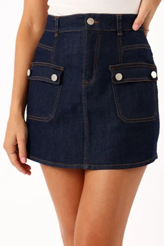 An indigo denim cargo mini skirt with two buttoned flap pockets and belt loops.