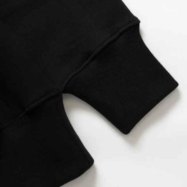 The ribbed cuff and hem band of a black sweatshirt, close up.