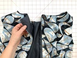 A concealed zip between two printed dress panels, with the dark bodice lining folded back.