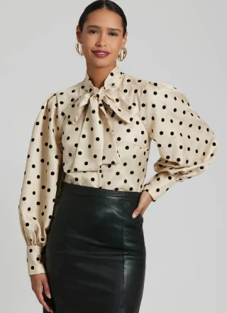 A cream polka-dot blouse with full bishop sleeves gathered into deep buttoned cuffs.
