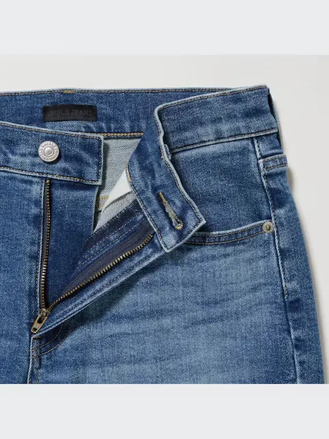 An open zip fly on dark blue jeans, below a metal waistband button.