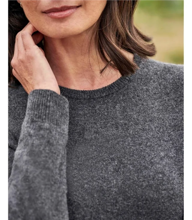 A woman in a fine grey knit sweater with a narrow ribbed neckline.