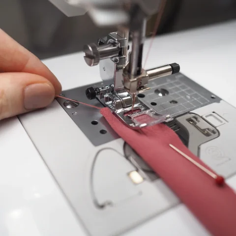 Fine silk fabric under the presser foot of a sewing machine.