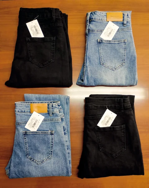 Four pairs of finished jeans folded with barcode tags before packing.