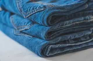 Folded blue jeans showing the wash and stitching.