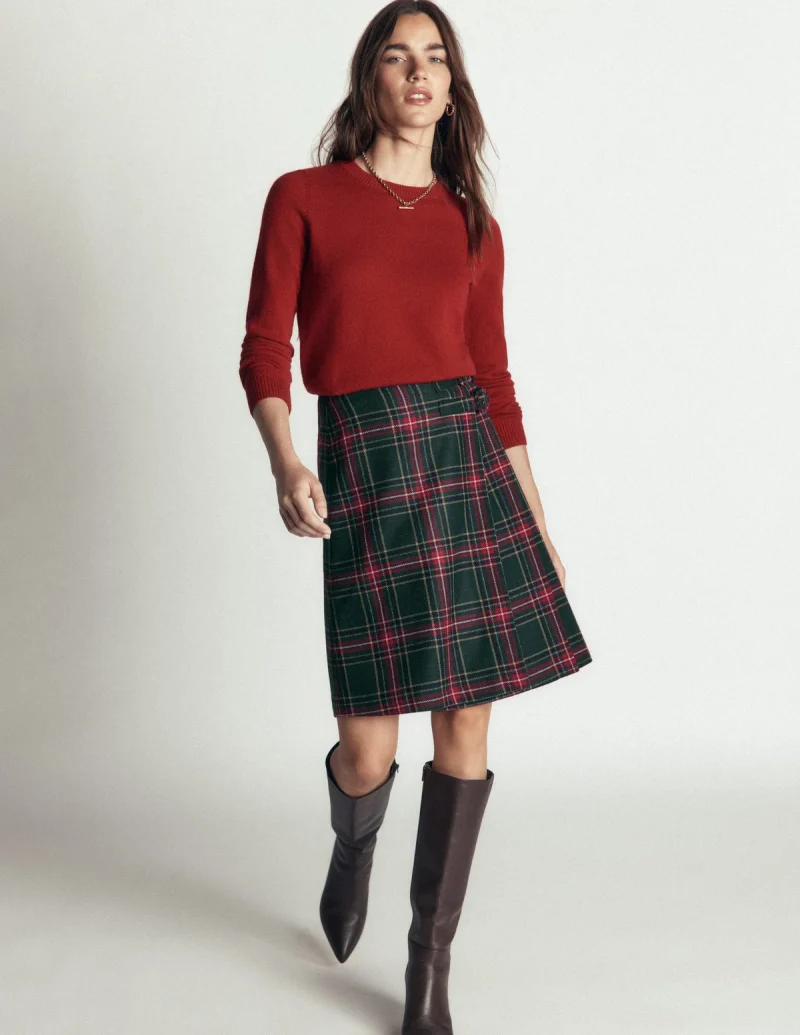 A green tartan kilt skirt with a flat front and pleats at the sides.
