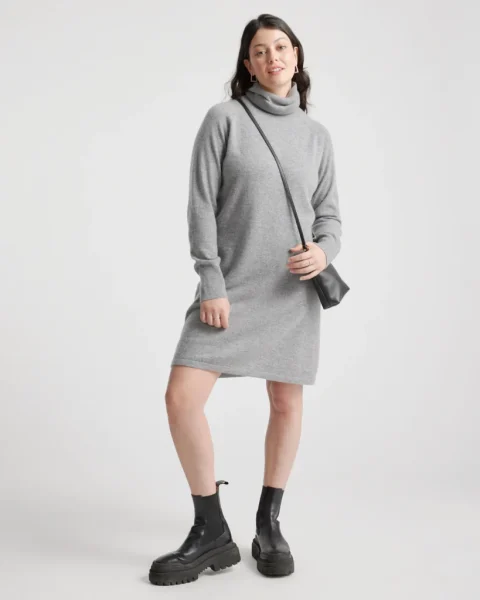 A gray turtleneck sweater dress with long sleeves, worn with chunky black boots.