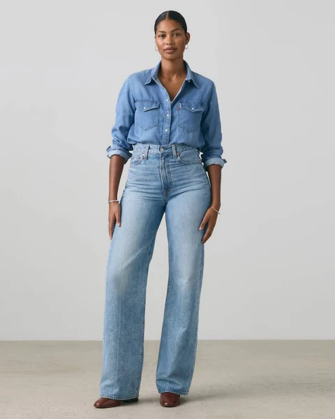 A woman in light blue high-rise wide-leg jeans and a denim shirt.