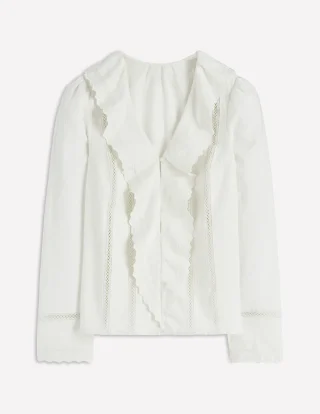An ivory blouse with long sleeves, embroidered trim and ruffles down the front.