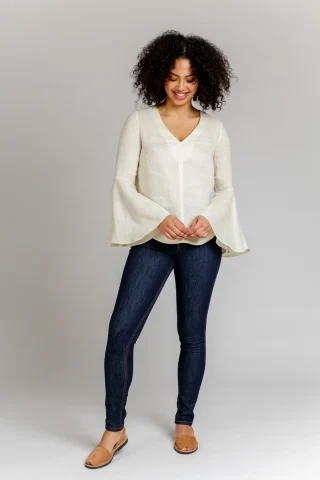 An ivory V-neck blouse with wide flared bell sleeves, worn with dark jeans.