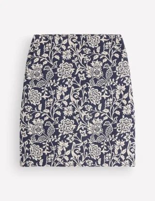 A navy and ivory floral jacquard A-line skirt laid flat.