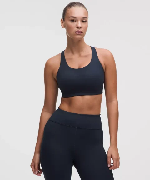A model in a navy racerback sports bra and matching high-waisted leggings.