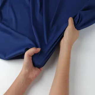 Hands stretching a piece of navy nylon-spandex knit.