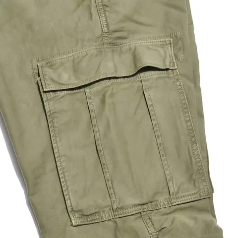 An olive cargo pocket with a buttoned flap and a pleat at its side.