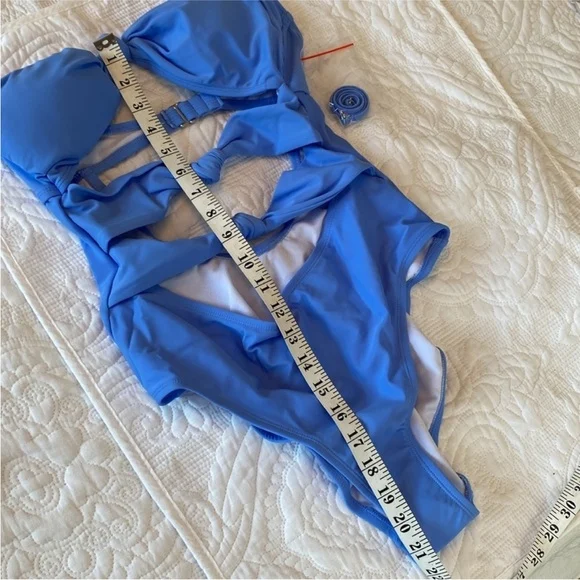 A blue one-piece swimsuit with a measuring tape laid along it on a quilted white cover.