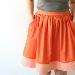 An orange gathered skirt with a flat waistband and a broad pink band along the bottom.