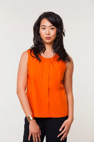 An orange sleeveless woven shell with a round neckline and a wide box pleat at center front.
