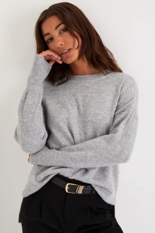 A woman in an oversized grey sweater with dropped shoulders.