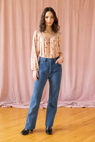 A peach printed peasant blouse with a gathered neckline and full raglan sleeves, tucked into jeans.