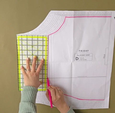 A printed multi-size paper pattern being checked with a ruler.