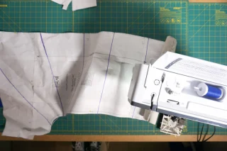 Quilting lines marked on a coat panel positioned at a sewing machine.
