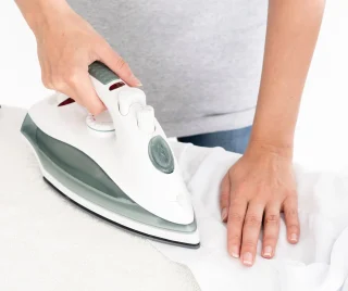 Satin being pressed with an iron through a protective cloth.