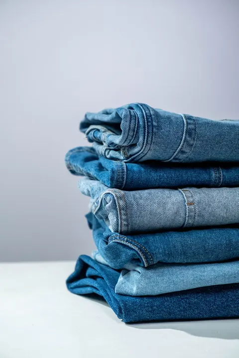 A stack of folded blue jeans in several washes.