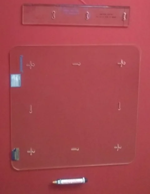 Shrinkage measuring template, ruler and permanent fabric marker on red fabric.