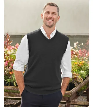 A man in a dark V-neck sweater vest over a white shirt.