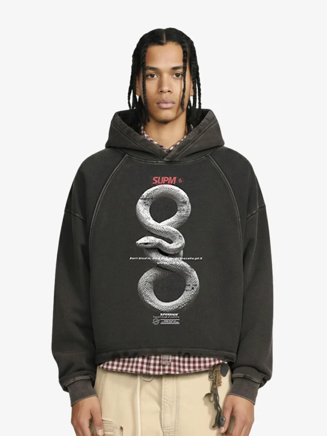 A model in a washed charcoal hoodie with a large front graphic and dropped shoulders.