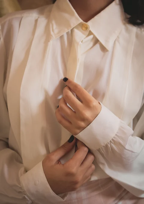 A white blouse with long sleeves and finished cuffs.