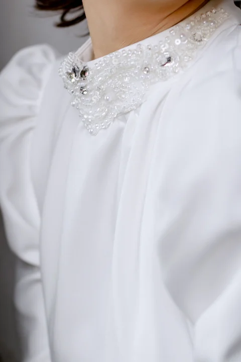 A white blouse with an embellished collar.