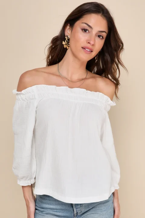 A white cotton blouse with an elasticated neckline below both shoulders and three-quarter sleeves.