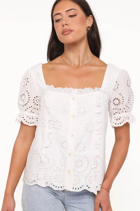 A white eyelet blouse with embroidered floral openings, a square neckline and scalloped sleeve and hem edges.