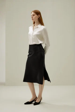 A white silky button-front blouse tucked into a black midi skirt.