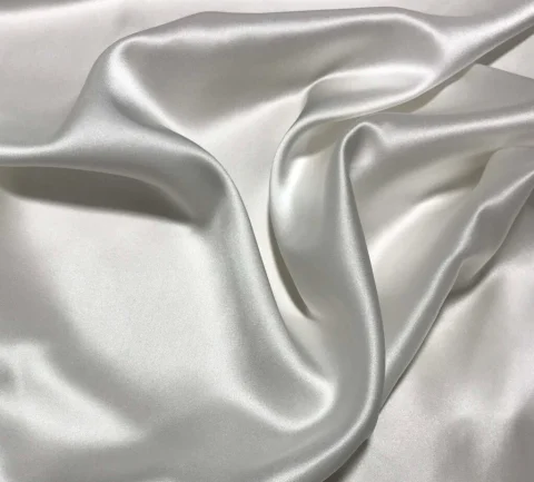 White silk charmeuse with a soft sheen, lying in loose folds.