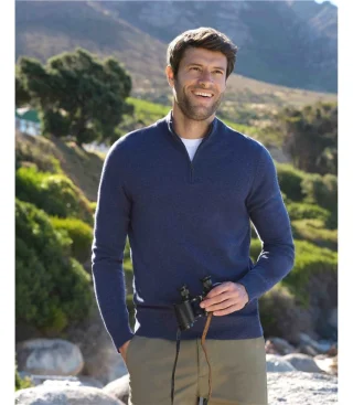 A man in a navy quarter-zip sweater standing outdoors.