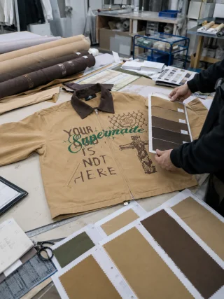 The sand jacket front on a table beside brown and sand shade cards during the color review.