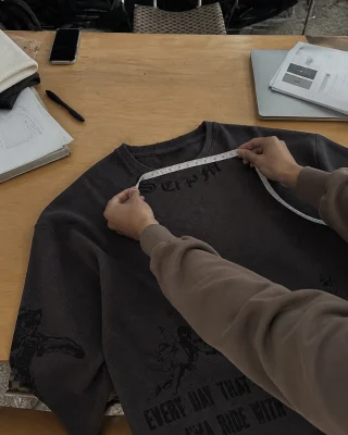 A measuring tape across the charcoal waffle long sleeve with dark lettering.